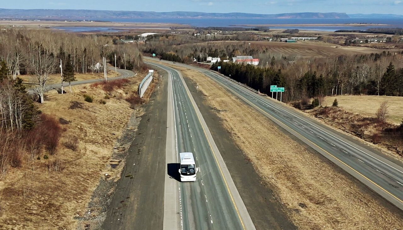 An aerial of a coach-style bus travelling on Highway 101 near Wolfville.